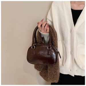 Dettaglio della borsa vintage in pelle lucida marrone scuro con anelli e finitura testurizzata