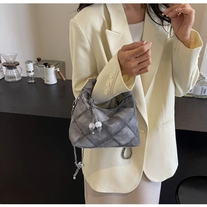 Detail der grauen gesteppten Denim-Tasche mit Perlenanhänger und Silberkette