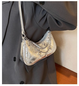 Detail of silver metallic crescent bag with quilted texture and heart charm chain