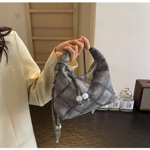 Details einer blauen Denim-Hobo-Tasche mit Silberkette und weißem Perlen-Reißverschluss