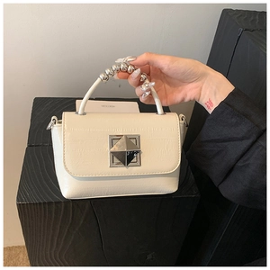Détail d'un sac en similicuir crème avec poignée à billes argentées et fermoir carré chic