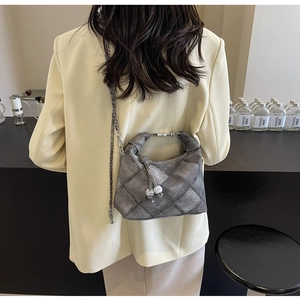 Detail der taupefarbenen Stepptasche mit Metallgriffen und Perlen-Reißverschlussanhänger