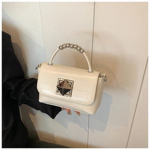 Détail du sac en cuir crème avec poignée à perles argentées et boucle carrée en métal