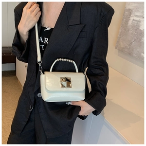 Petit sac carré crème chic avec poignée en perles et boucle en métal sur tenue noire