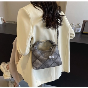Detail der grauen Vintage-Tasche mit Rautenmuster-Patchwork und Metallkettenriemen