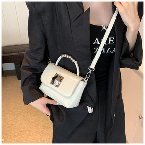 Détail d'un sac en faux cuir crocodile blanc cassé avec fermoir pyramide doré et poignée