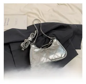 Detail of silver quilted crossbody bag with metal chain on a dark grey suit fabric