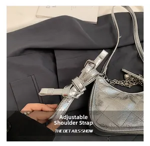 Detail of adjustable shoulder strap and silver quilted texture on metallic crossbody bag
