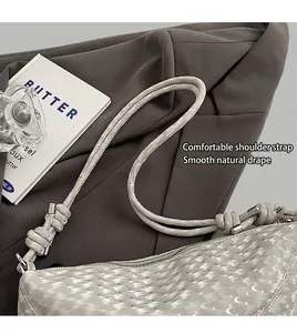 Détail du sac tressé gris avec bandoulière à nœuds élégants et détails en métal argenté