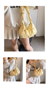 Detail of light yellow cloud bag featuring pleated handles and secure metal zipper