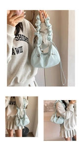 Macro shot of light blue dumpling bag featuring ruched handle and metal adjustment buckle