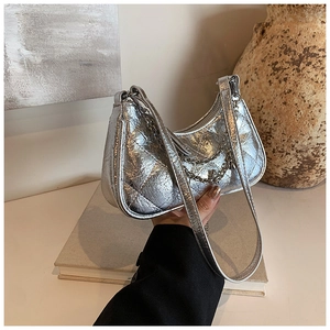 Detail of silver quilted hobo bag with metallic finish and chain strap on art books
