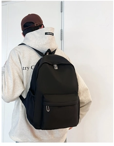 Macro side view of a black minimalist nylon school backpack with silver oval zippers