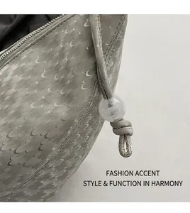 Détail du sac bandoulière gris montrant les motifs de croissant et cordon perlé