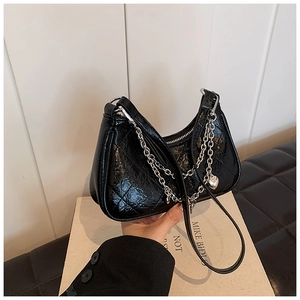 Close-up of black quilted leather shoulder bag with silver chain and heart pendant