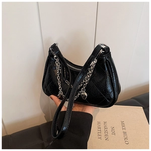 Detail view of black quilted faux leather bag with silver chain and heart charm