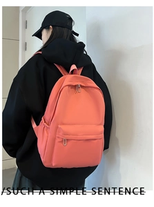 Detail view of pink nylon backpack on model showing large capacity and side pocket