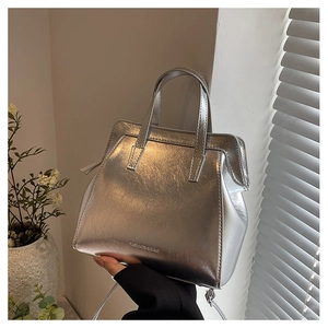 Detail of silver metallic handbag with dual top handles and detachable shoulder strap