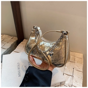 Detail of gold metallic pleated handbag with double chain and heart pendant