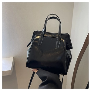 Close-up of a glossy black crossbody bag featuring smooth finish and fashion bag embossing
