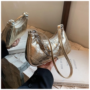 Close-up of golden quilted shoulder bag featuring metallic crinkled texture and silver chain