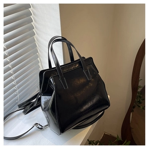 Close-up of elegant black patent leather handbag featuring glossy finish and metal feet