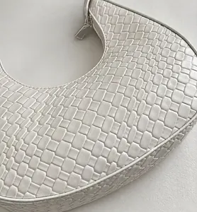 Close-up of elegant white woven leather texture and silver zipper on the crescent bag