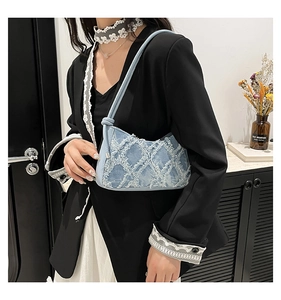 Dettaglio borsa sottobraccio in denim con motivo a rombi a frange bianche sfilacciate