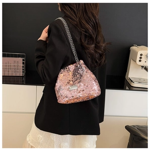 Detail of pink sequin bucket bag with silver chain straps and polished metal plate