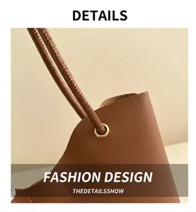 Close-up of brown leather tote bag featuring gold metal eyelets and round handles