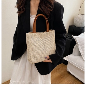 Close-up of beige handwoven straw tote bag with brown leather handles and V-shape pattern