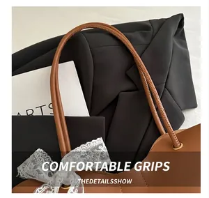 Close-up of brown tote bag featuring elegant white lace bow and slim round handles