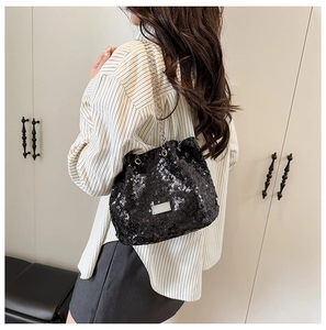 Detail of a black sequin bucket bag featuring a metallic nameplate and elegant chain strap