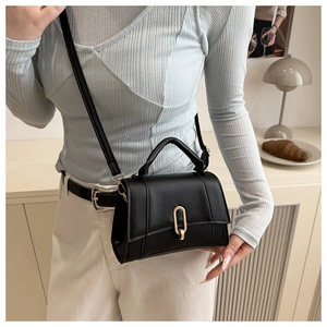 Détail d'un sac à main en cuir noir avec boucle dorée et bandoulière longue réglable