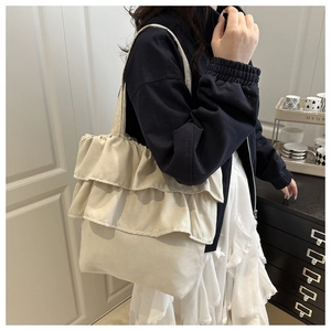 Close-up of beige canvas tote bag showing ruffled edges and reinforced handles detail