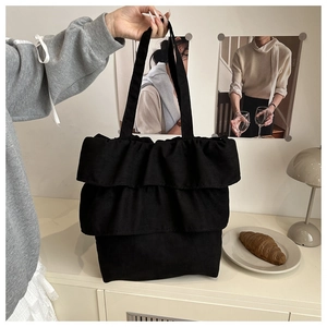 Close-up of black layered ruffle tote bag in cotton canvas with elegant pleated design