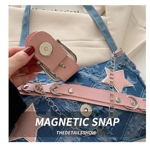 Detail des Magnetverschlusses und des Used-Denim-Stoffs an einer Stern-Schultertasche