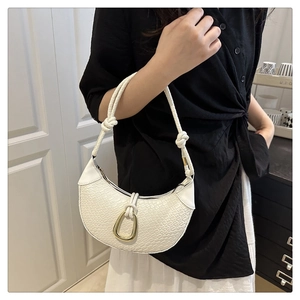 Close-up of white woven crescent bag with gold metal buckle and knotted shoulder strap