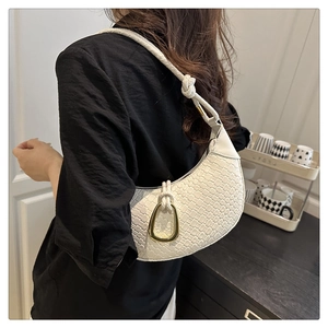 Detail of white woven hobo bag with gold triangle buckle and braided shoulder strap