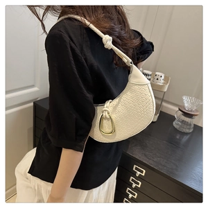 Détail du sac demi-lune blanc montrant la texture tressée et la poignée nouée dorée