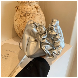 Detail of silver pleated cloud bag featuring metallic texture and drawstring handle design