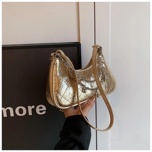 Close-up of metallic leather quilted bag with gold chain strap and heart charm detail