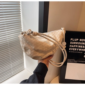 Detail of cream crescent bag with jacquard texture and stylish knotted shoulder strap