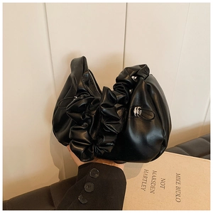 Detailed view of black pleated cloud bag with metallic clasp and soft PU leather texture