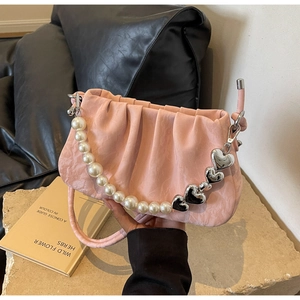 Detail of pink pleated handbag featuring pearl strap and silver heart-shaped charms