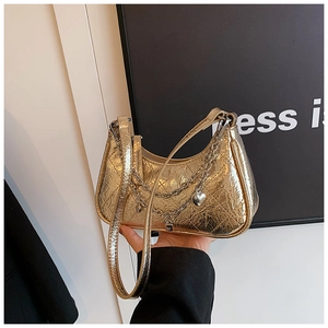 Detail of gold quilted crescent bag featuring metallic chain and heart lock pendant