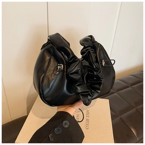 Detail of black pleated cloud handbag featuring leather texture and metallic drawstring buckle