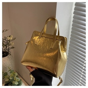 Detail of metallic gold handbag featuring dual round handles and stylish chain strap
