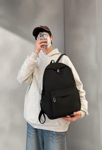Spacious black nylon backpack with front zip pocket shown on a male model back