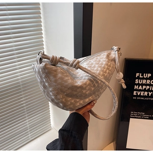 Detail of silver-grey hobo bag with scale texture and knotted handle knot design